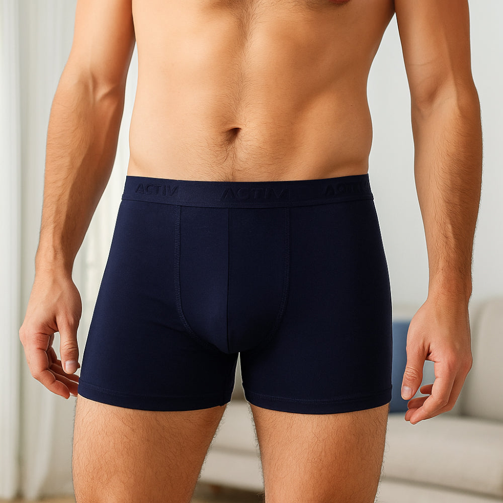 Man wearing navy blue boxer briefs with a blurred background