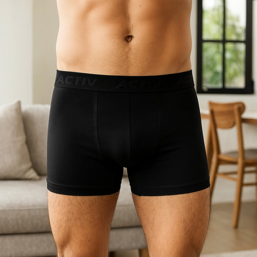 Person wearing black boxer briefs with 'Activ' waistband in a home setting.