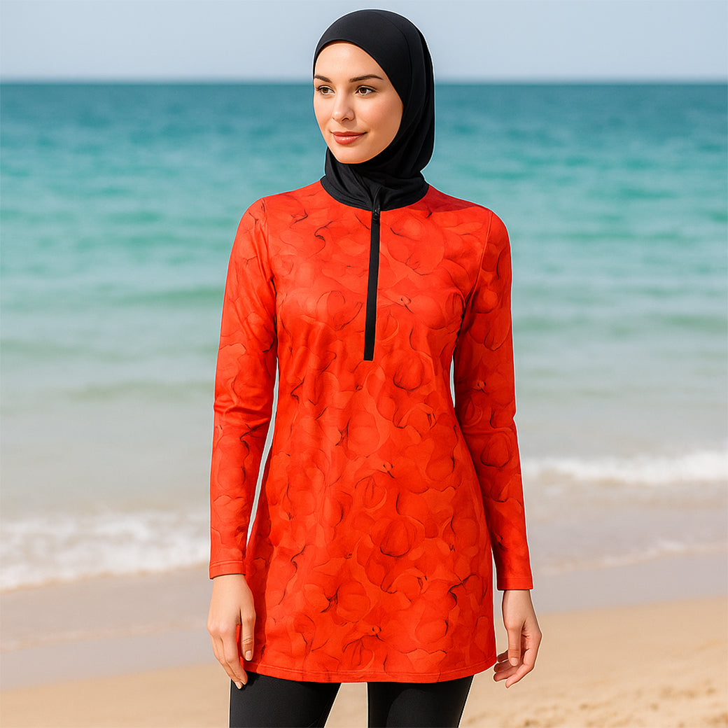 Woman wearing a red patterned swimsuit cover-up on a beach with ocean in the background